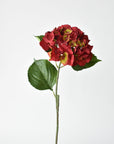 Artificial red hydrangea stem at an angle with three large green leaves