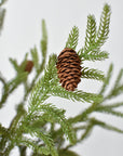 Close-up of real pinecones hand-finished onto a faux Norfolk pine branch