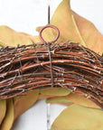 Back of faux magnolia wreath showing grapevine ring and built-in hanging loop