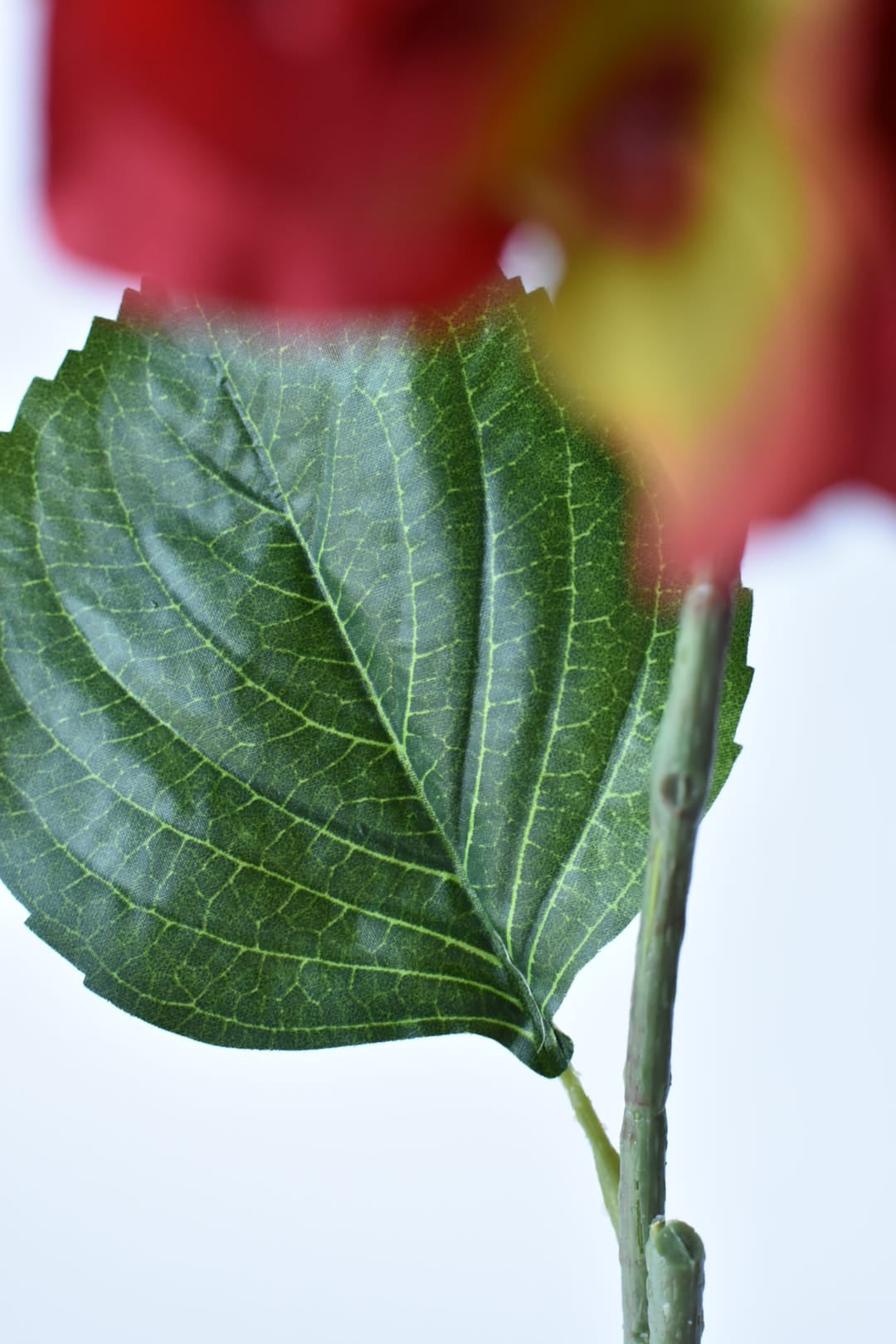 Side view of a faux red hydrangea head on a wired stem