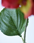 Side view of a faux red hydrangea head on a wired stem