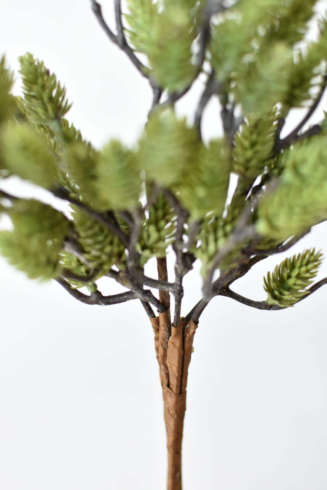 Close-up of green faux pinecones clustered along a wired branch