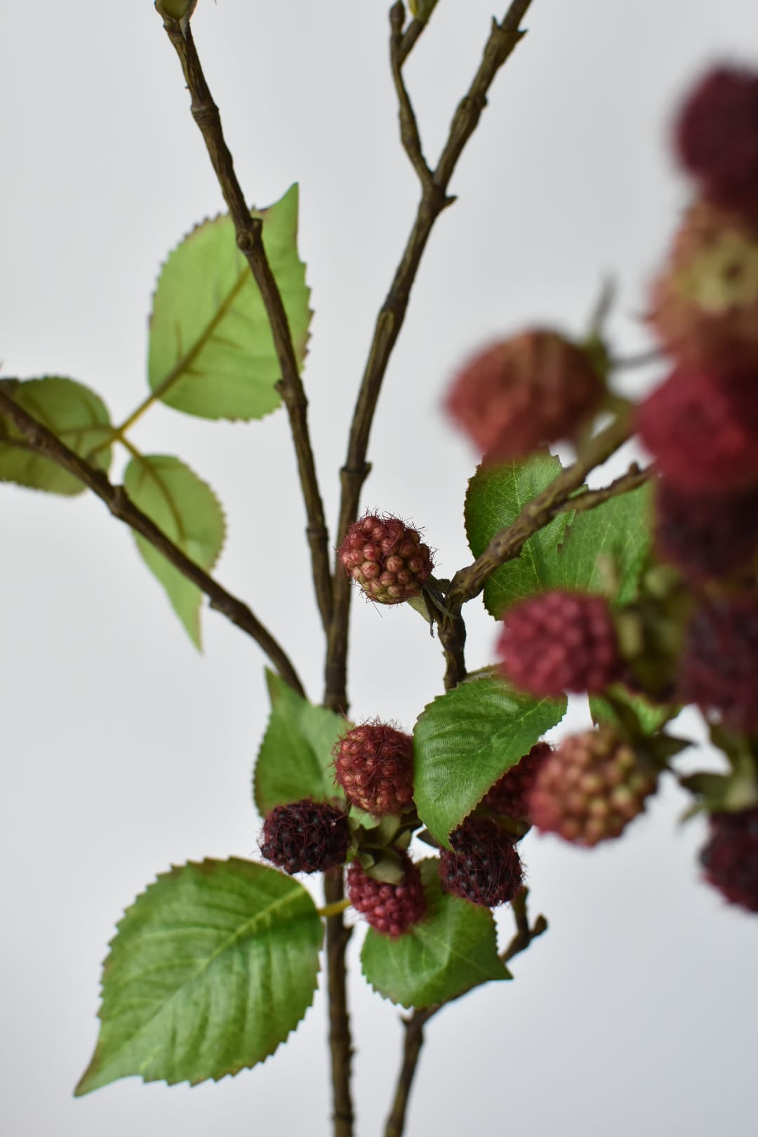 Detail of purple and mauve faux raspberries clustered along a wired branch