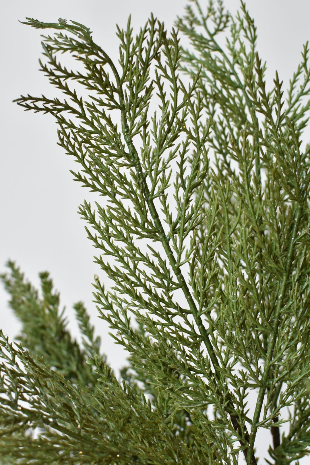 Artificial frosted cedar bundle from the side with its wired stems fanned open