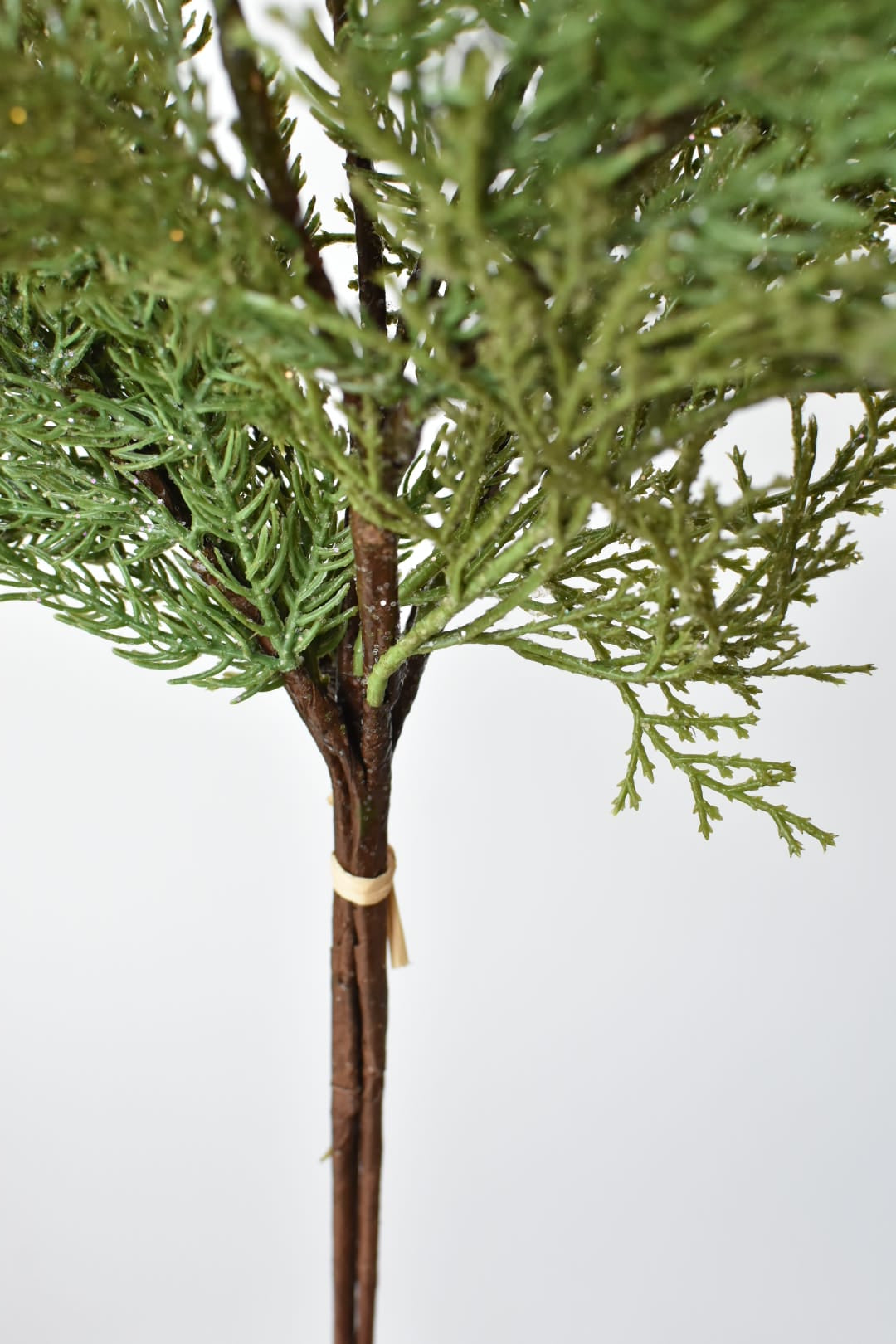 Detail of green faux cedar with clear glitter finish on a wired stem