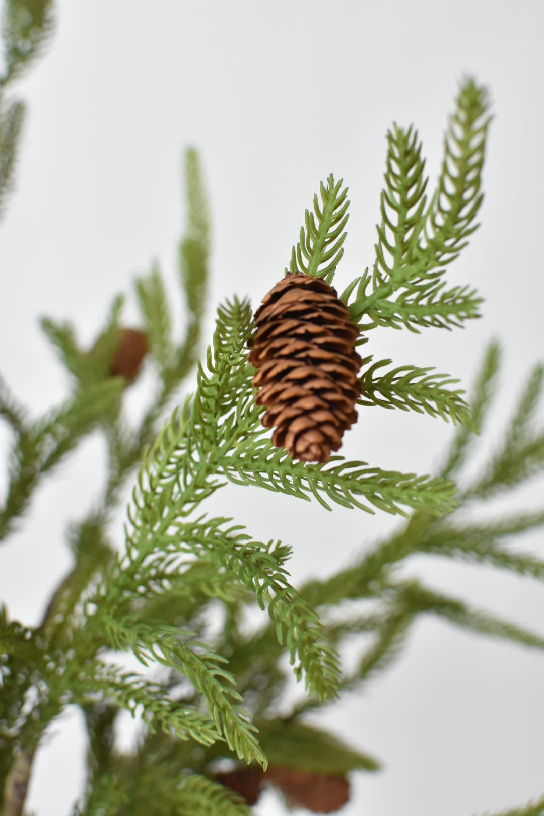 Close-up of real pinecones hand-finished onto a faux Norfolk pine branch