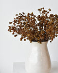 Three faux dried brown gypsophila stems arranged in a container