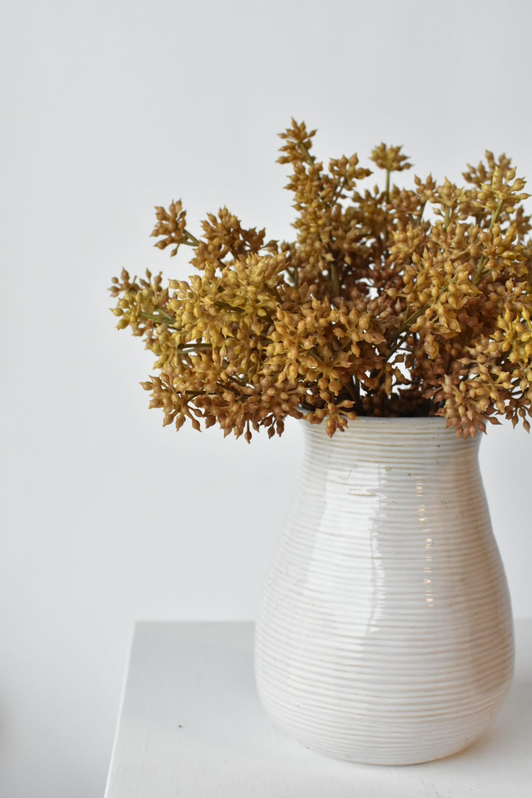 Three faux beige sedum bundles arranged together in a vessel