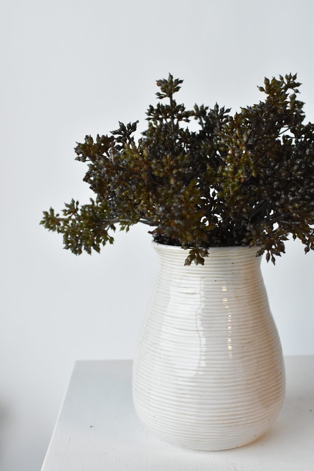 Faux dark brown and green sedum bundles arranged in a vessel