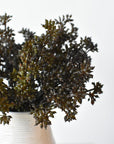 Multiple faux brown and green sedum bundles filling a small vessel