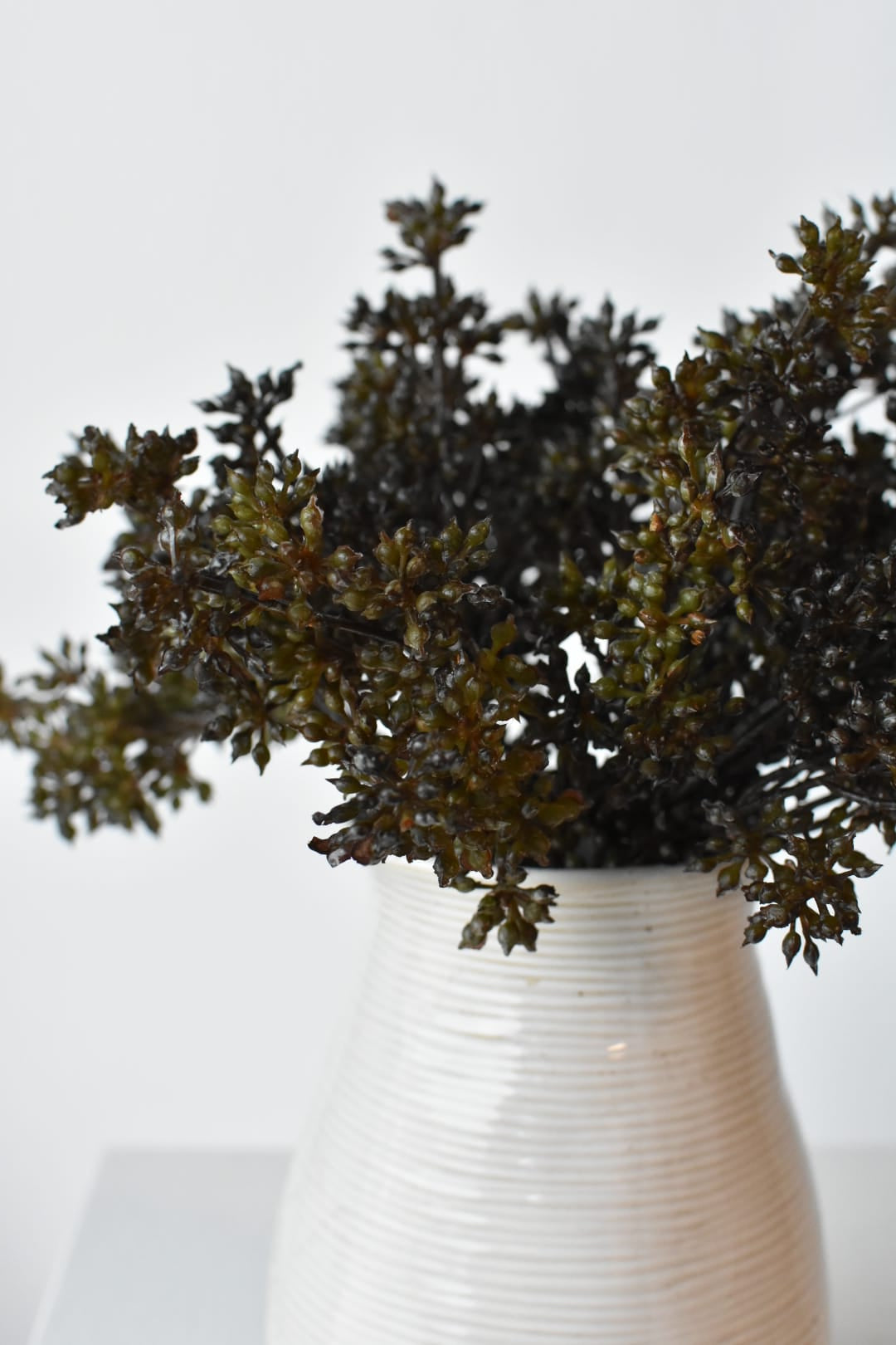 Faux dark brown sedum bundles in a vase showing berry texture and depth