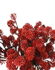 Close-up of dark red faux sedum berries mounded in a vessel