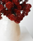 Three faux red sedum bundles filling a low container for a fall arrangement