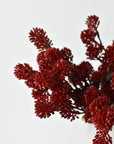 Faux red sedum bundles in a vessel showing depth of color across the clusters