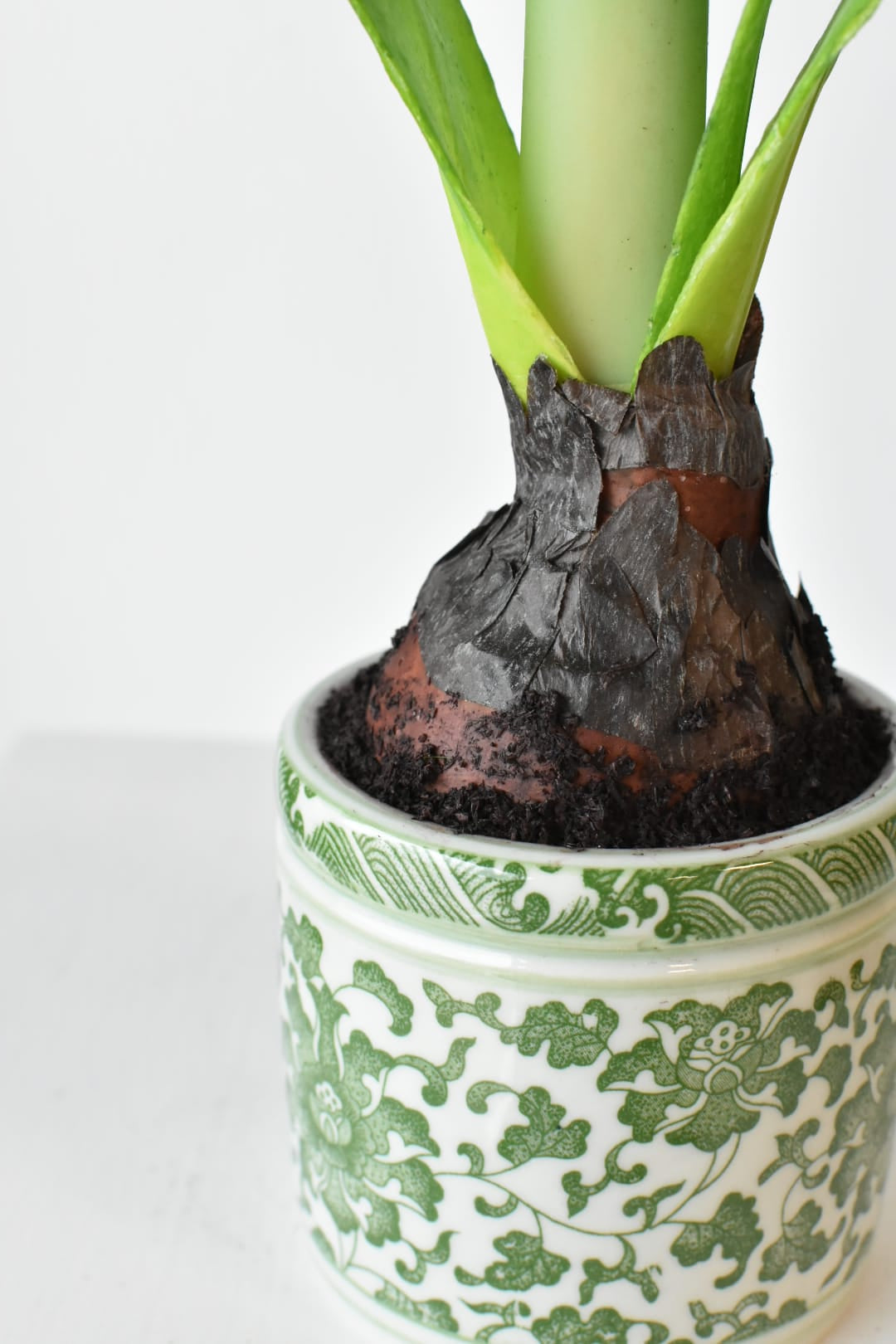 Green porcelain pot holding the faux white amaryllis