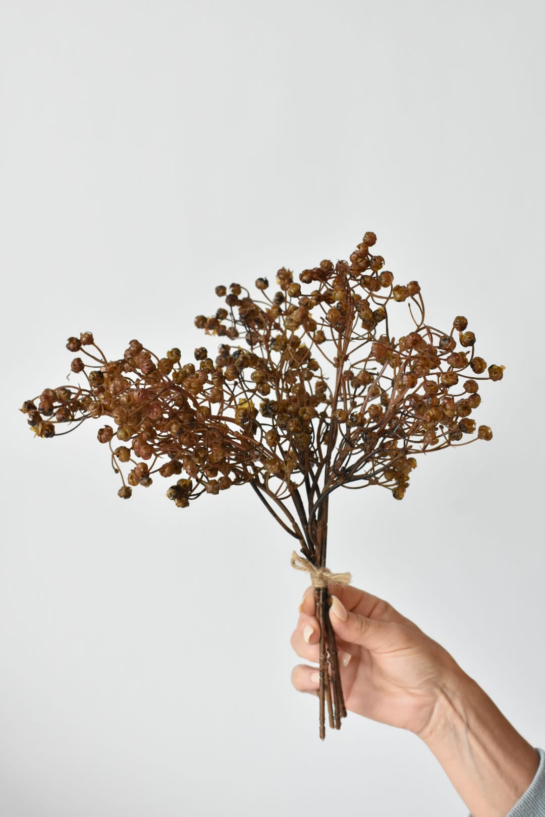 Hand holding a 13.5-inch faux dried brown baby's breath bundle