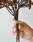 Faux dried baby's breath bundle in hand showing the twine tie at the base