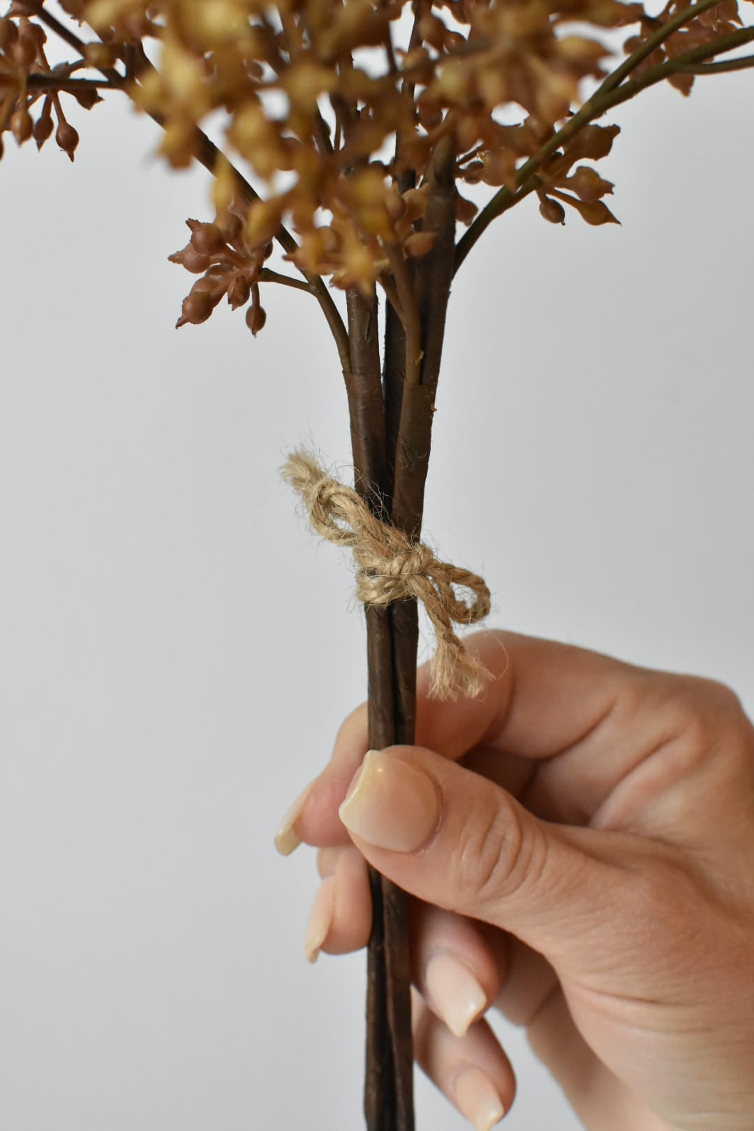 Faux beige sedum bundle in hand showing gradated color across the berries