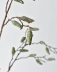 Close-up of gray-washed green pods on a faux pod spray branch stem
