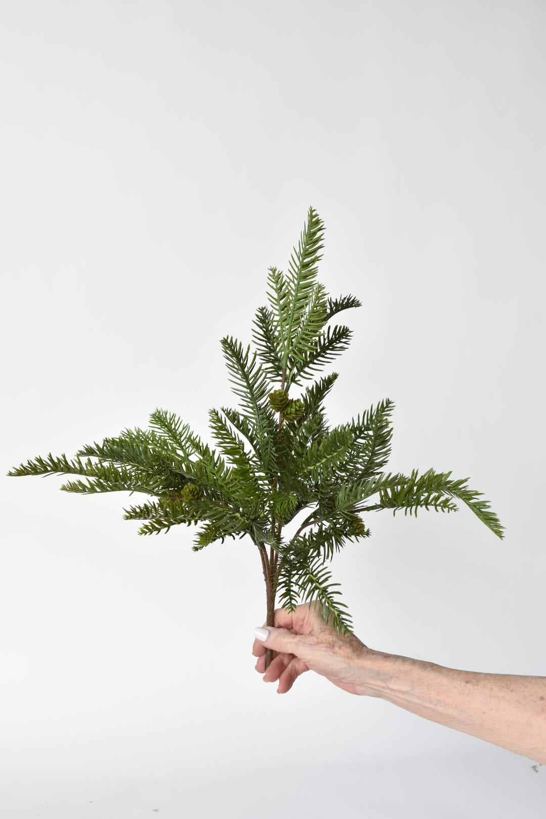 Close-up of faux pine needles and small pine cones on a wired bush