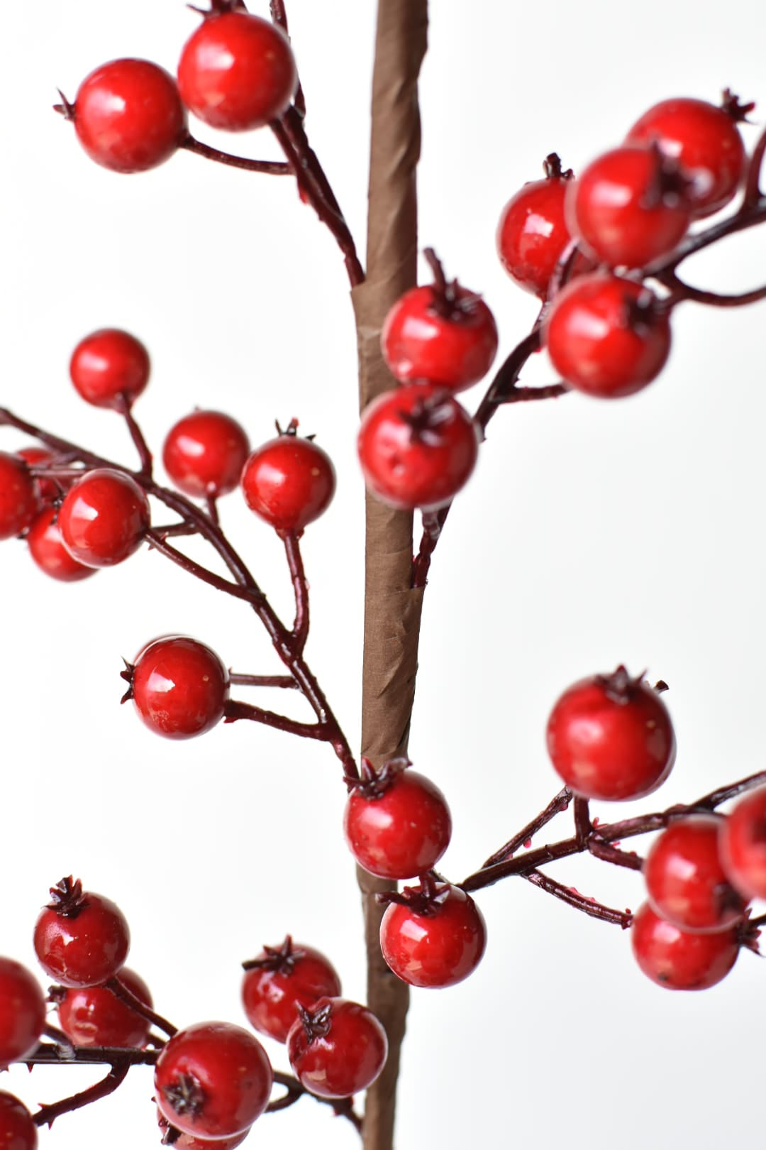 Glossy red faux berries on paper-wrapped wired stems