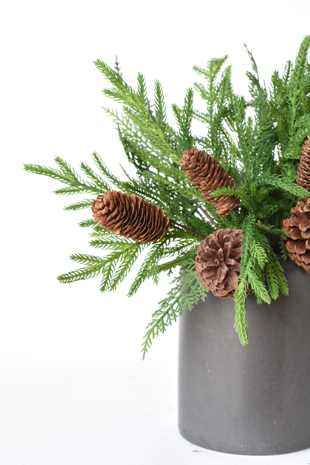 Three faux pine and cedar bushes styled together in a container