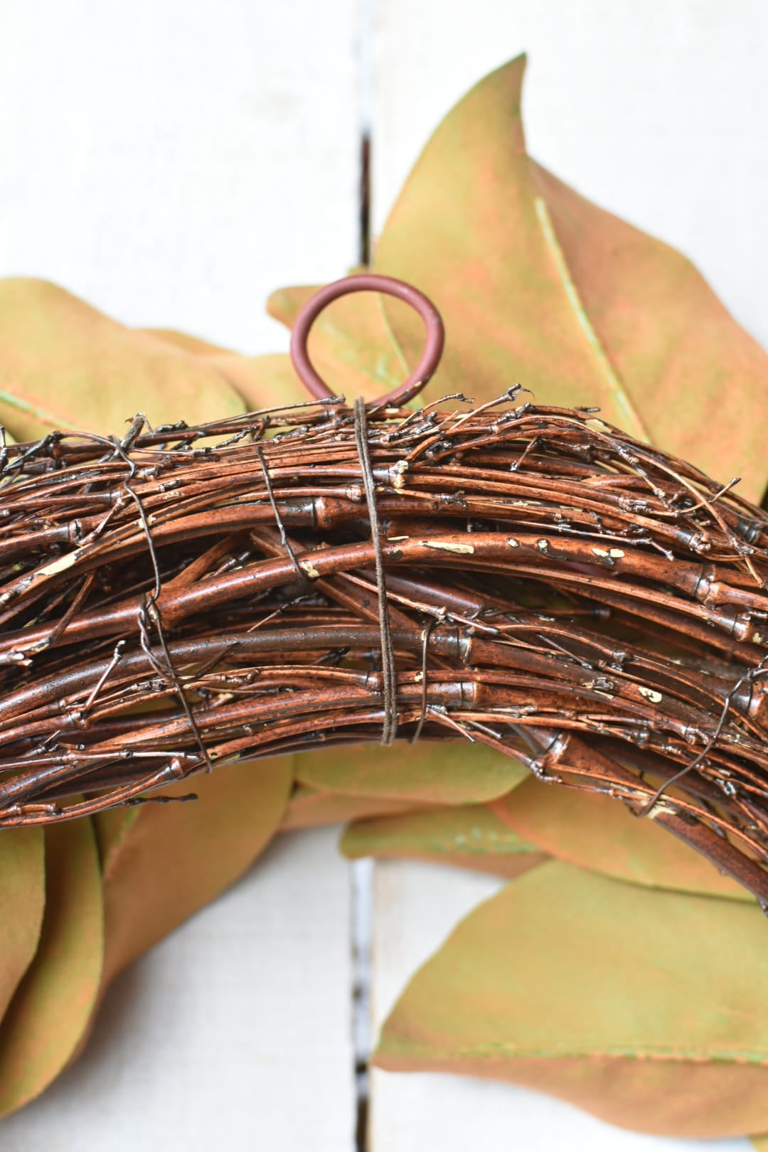 Back of faux magnolia wreath showing grapevine ring and built-in hanging loop