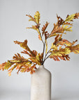 Three faux oak leaf branches in a tall vase