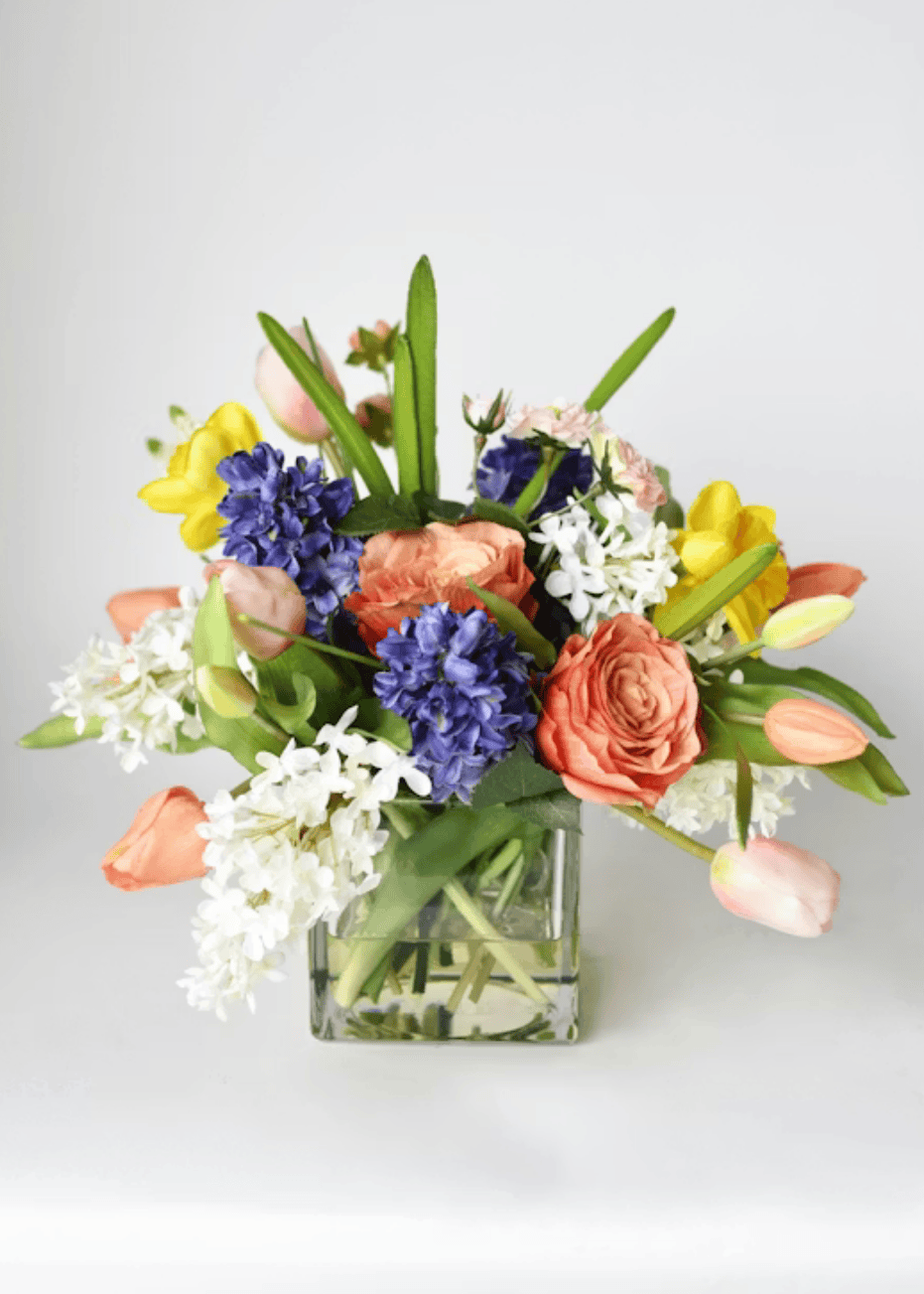 Colorful flower arrangement in a glass vase on a light gray background